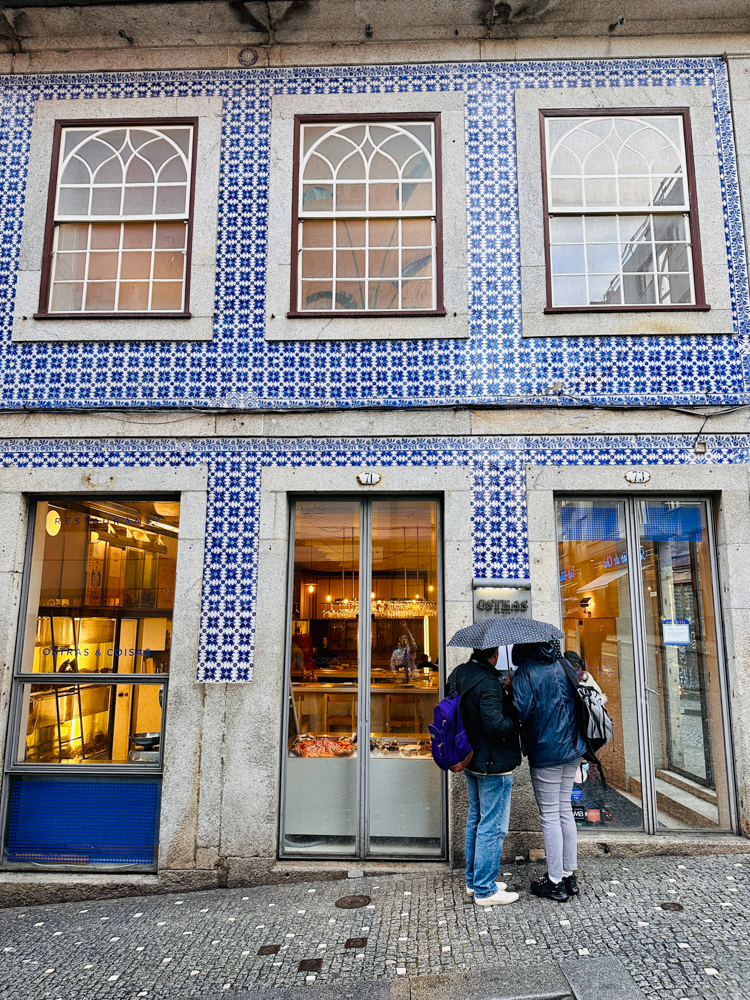 Couple holding an umbrella looking inside a bakery