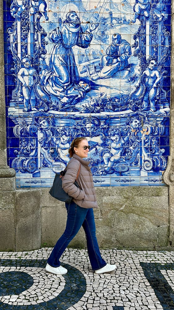 Rachelle walking by blue tiles in Porto, Portugal