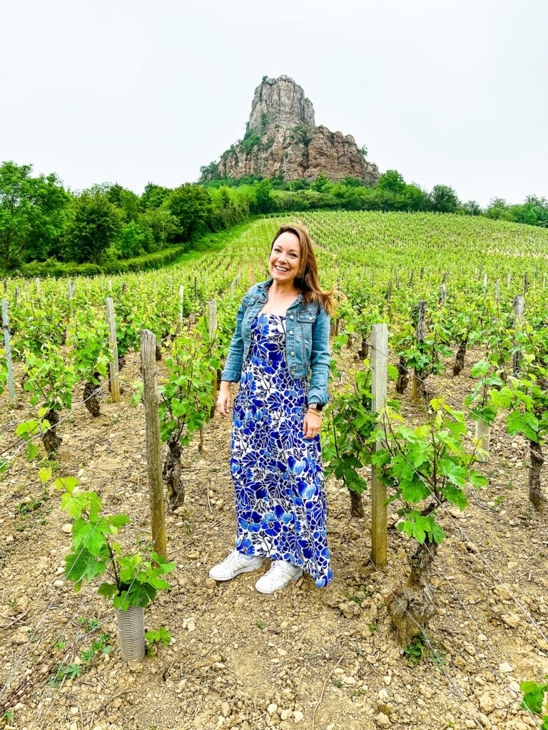 Rachelle standing in a vineyard wearing a blue dress.