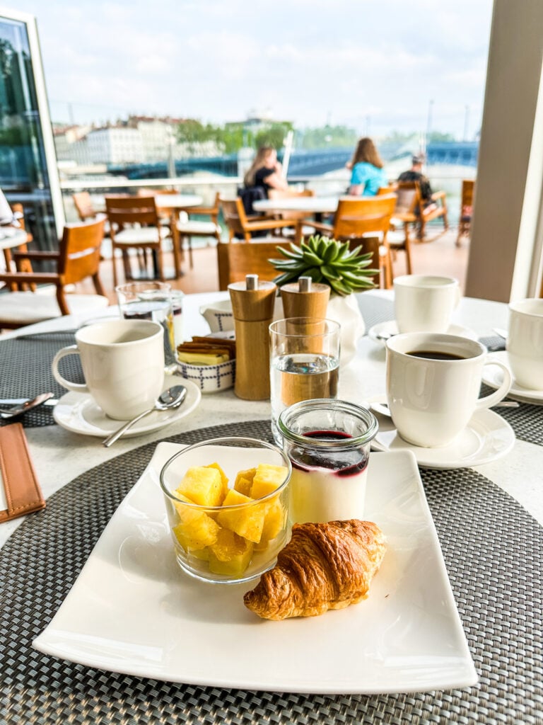 Breakfast on a Viking Cruise showing a croissant, fruit, and yogurt and coffee.