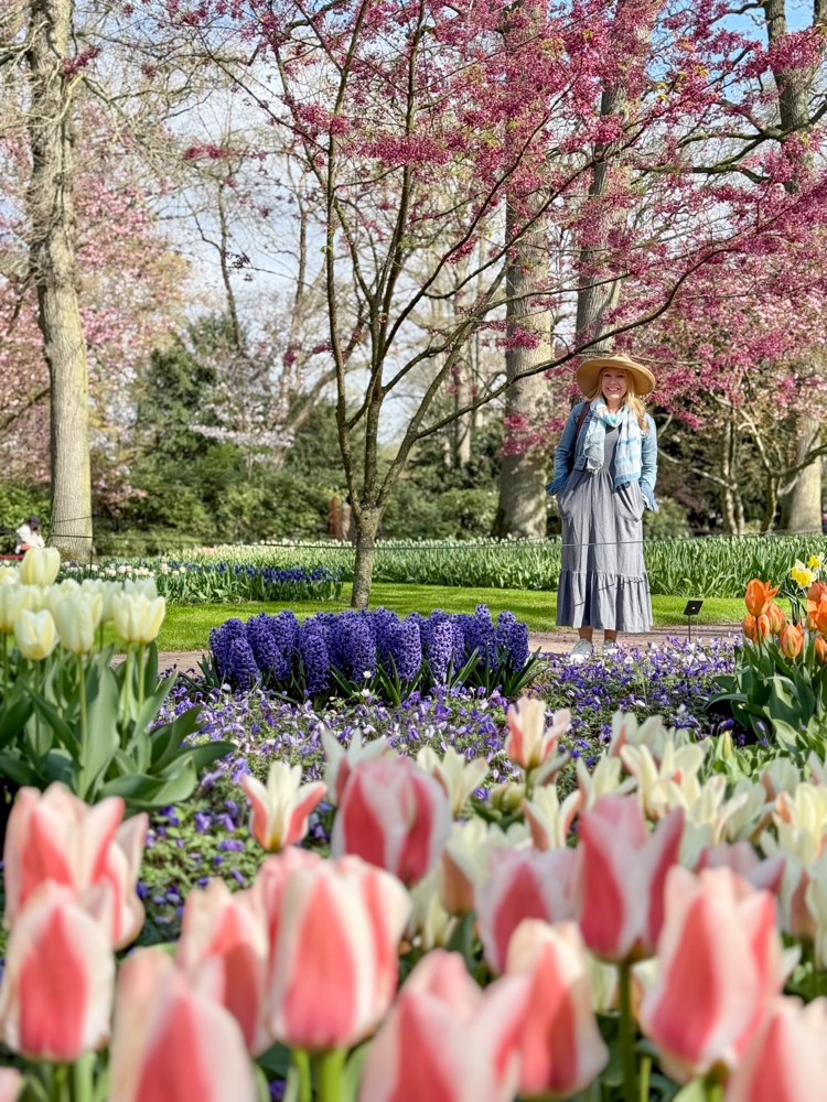 Rachelle posing with purple and pink flowers in Keukenhof Gardens