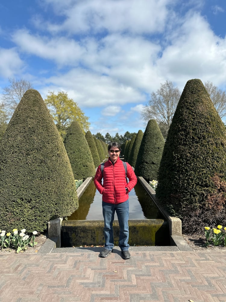 Pete standing between two topiary conical bushes