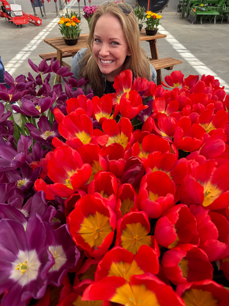 Rachelle posing for a photo next to purple and red tulips