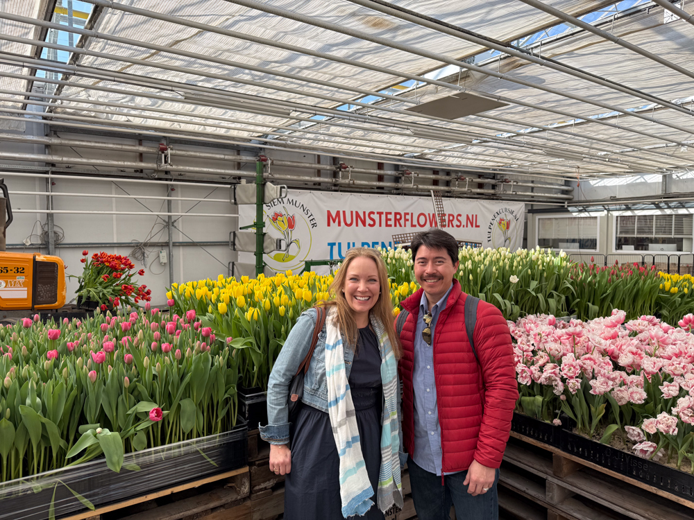 Rachelle and Pete posing next to tulips in a farm warehouse