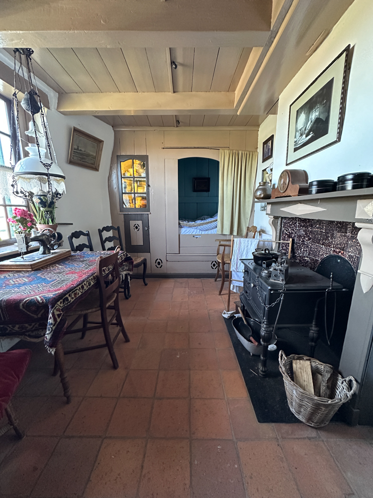 The inside of a windmill showing a dining tale, sleeping cubby, and fireplace