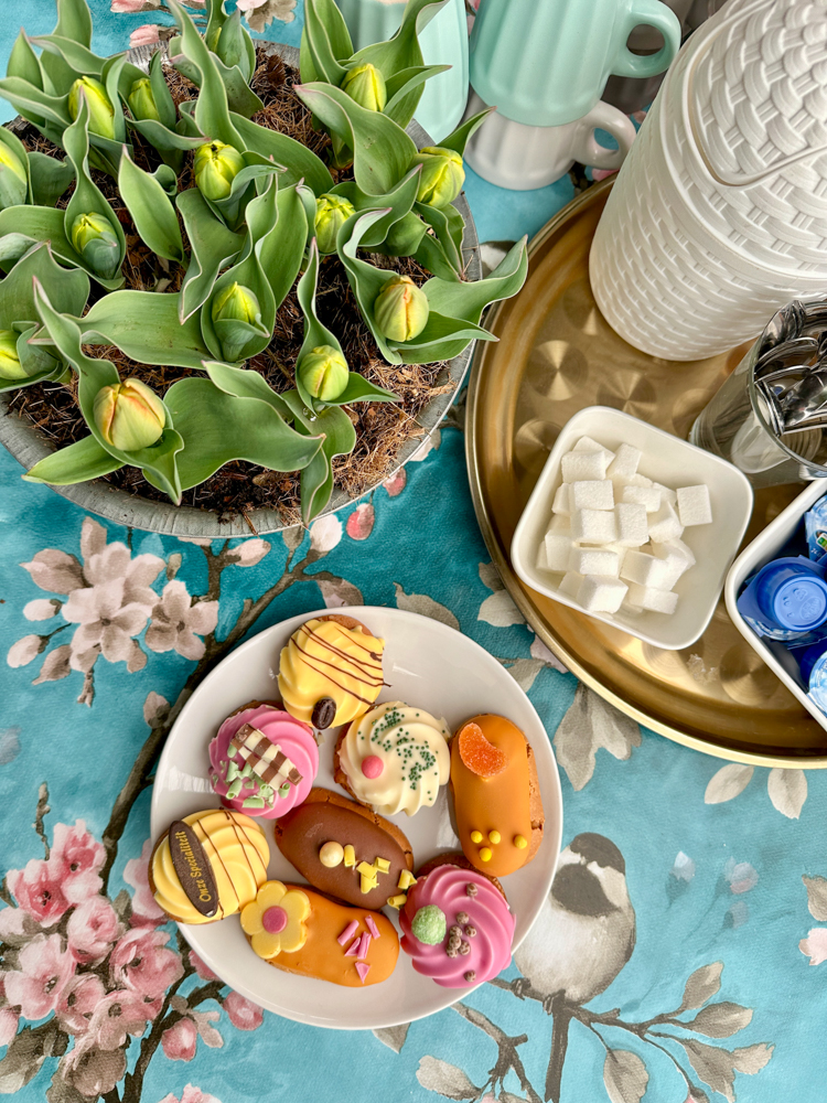 A plate of cookies next to a pot of unbloomed tulips
